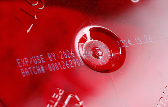 Expiration date and batch number printed on a red surface, indicating product freshness and traceability.