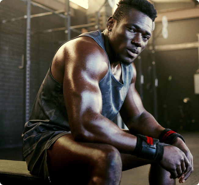 A person in a gym setting, wearing workout attire, sitting on a bench, possibly after exercising.
