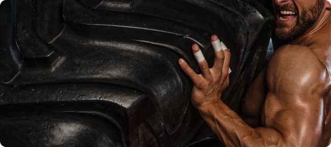 Man lifting a large tire, showcasing strength and fitness.